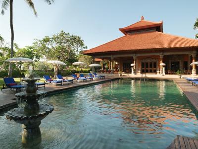Large swimming pool in front of an Asian-inspired building with red roof and poolside lounge chairs