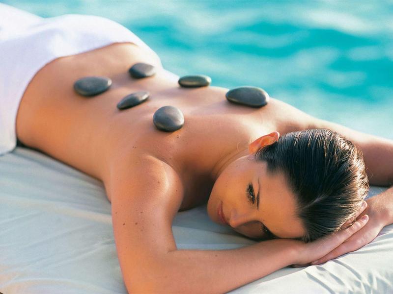 Woman relaxing with hot stones on back near water