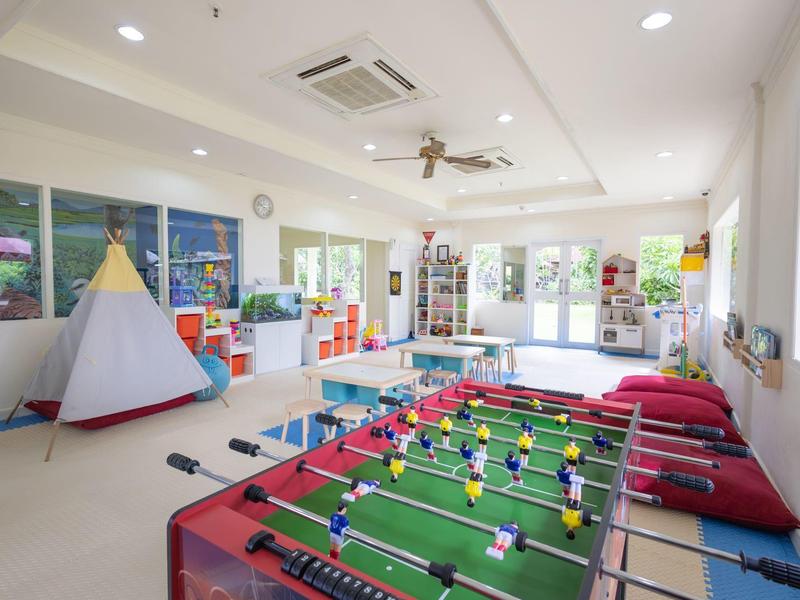 Bright playroom with foosball table, rug, teepee, and cushions.
