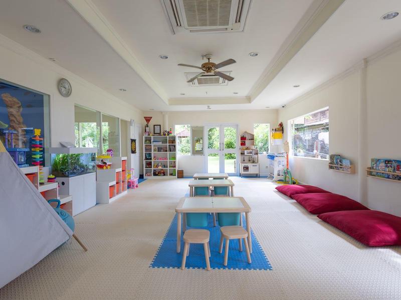 Bright, modern room with kids' nooks, floor cushions, and small tables for activities in a hotel area.