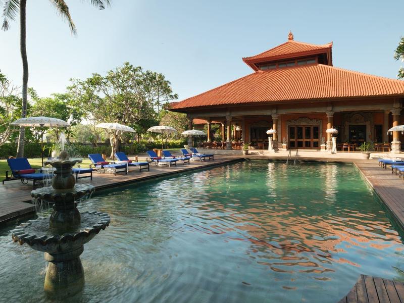 Large swimming pool in front of an Asian-inspired building with red roof and poolside lounge chairs