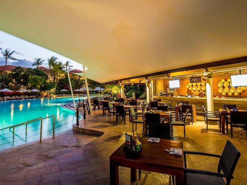 Evening atmosphere at a modern hotel pool with bar and seating under a roof