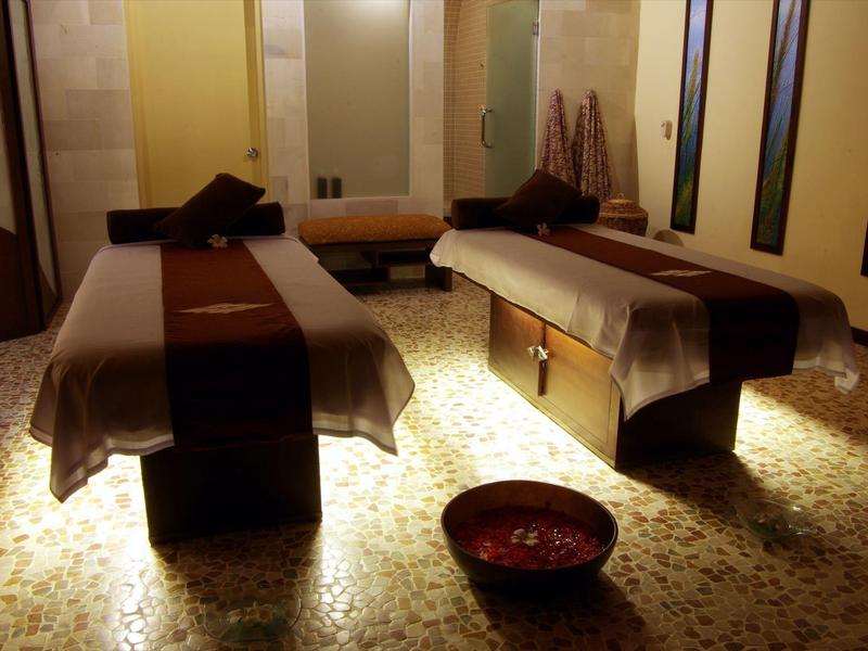 Treatment room with two massage tables, soft lighting, and oriental decor.