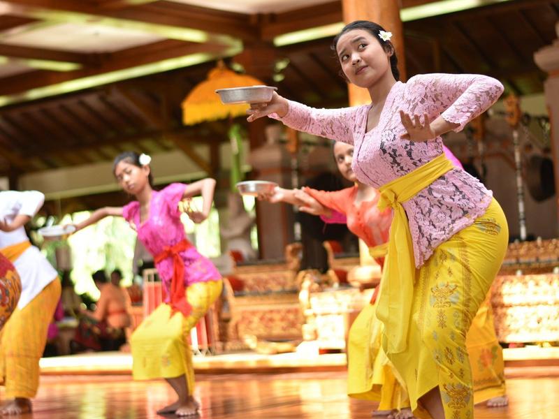 Dancers in colorful traditional costumes perform a dance in a decorated indoor setting.