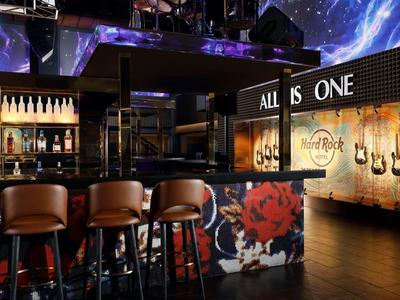 Bar dell'hotel moderna con sgabelli in pelle, decorazioni con chitarre e illuminazione d'atmosfera.