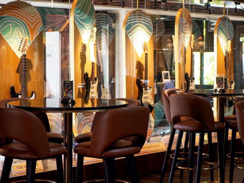 Vista interna di un bar con sgabelli alti e opere d'arte decorative colorate sulla parete.