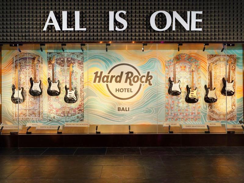 Vetrina illuminata dell'Hard Rock Hotel con chitarre elettriche appese e la scritta 'ALL IS ONE'.