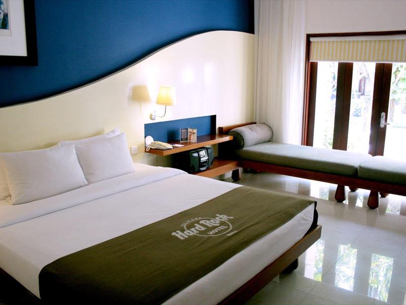 Camera d'hotel elegante con letto matrimoniale, comodino e panca vicino alla finestra.