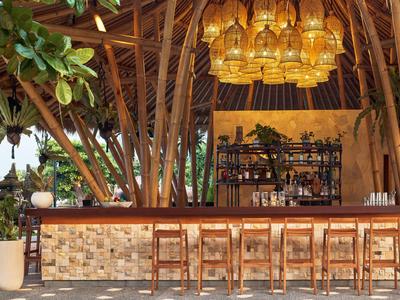 Moderner Hotelbarbereich mit Bambusstruktur und beleuchtetem Holzbarhocker-Arrangement