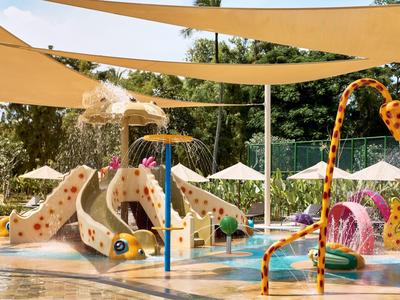 Bunter Wasser-Spielplatz mit Rutschen und schattenspendenden Segeln für Kinder in einem Hotel.