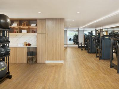 Moderner Fitnessraum mit Holzboden, Hanteln, Gymnastikbällen und Krafttrainingsgeräten.