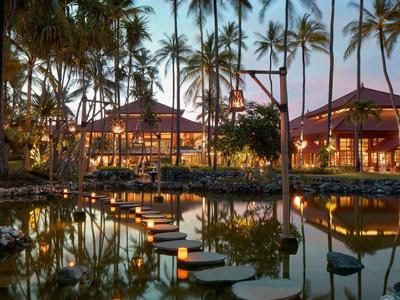 Ein beleuchtetes Resort mit Wasserwegen und Palmen bei Sonnenuntergang.