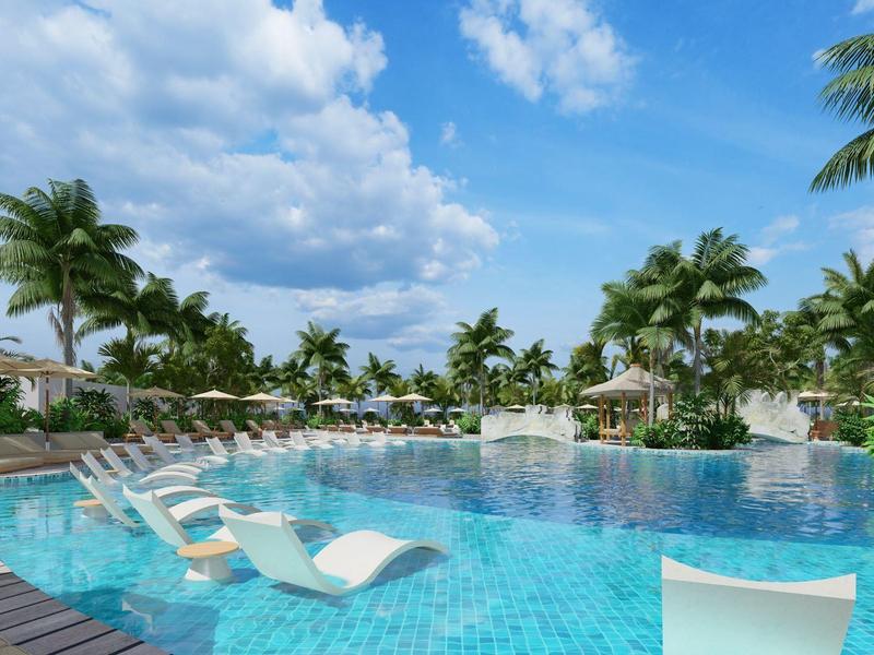 Großer Außenpool mit Liegestühlen, Palmen am Rand und blauem Himmel mit Wolken.
