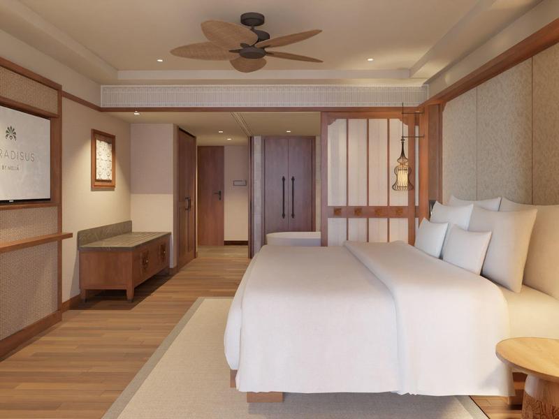 Modernes Hotelzimmer mit großem Bett, Holzmöbeln, Deckenventilator und warmem Lichtdesign.