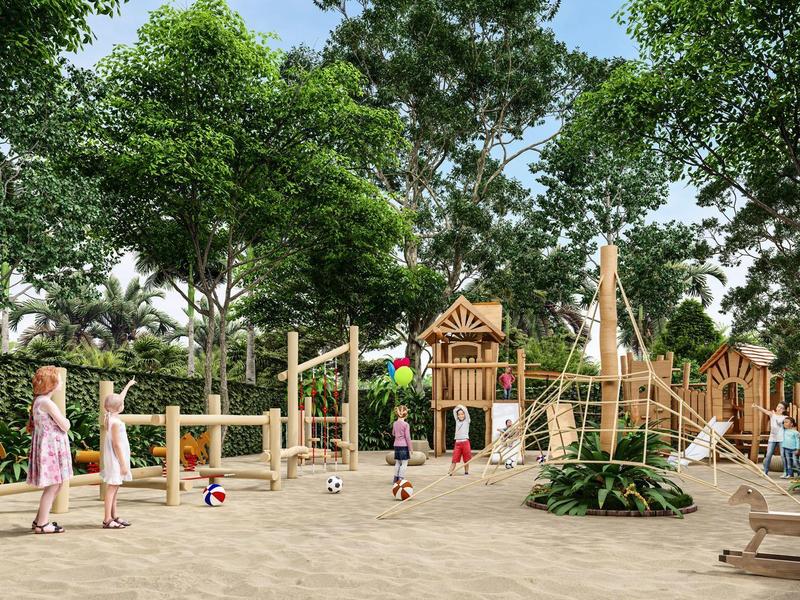 Kinder spielen auf großem Spielplatz aus Holz mit Klettergerüsten, Rutschen und Bäumen im Hintergrund.