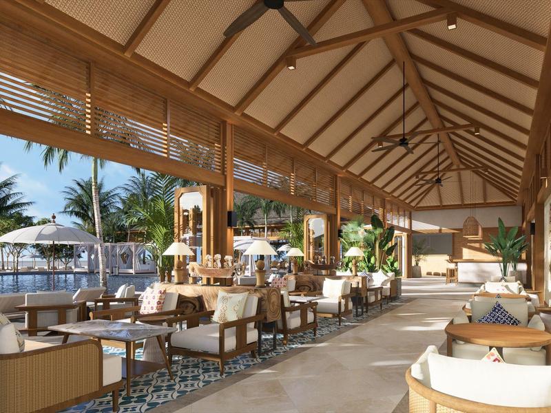 Geräumige, offene Lounge mit Holzdach, weißen Sesseln und Blick auf Pool und Palmen.