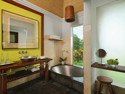 Modernes Badezimmer mit freistehender Badewanne, Holzdecke, gelber Wand und großem Fenster.