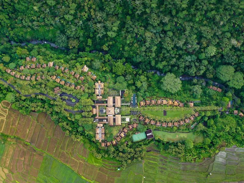 Luftaufnahme eines Dorfes mit Häusern, umgeben von dichtem Wald und Feldern.