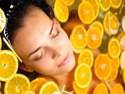 Vrouw ontspant met gesloten ogen in water gevuld met veel sinaasappelschijfjes