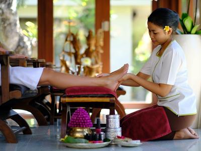 Vrouw krijgt voetmassage in ontspannen spa-omgeving met houten meubels en planten.