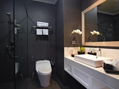 Modern hotelbadkamer met donkere douchehoek, witte toilet en wastafel.