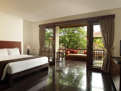 Moderne hotelkamer met groot bed, tv en balkon met uitzicht op groene bomen.