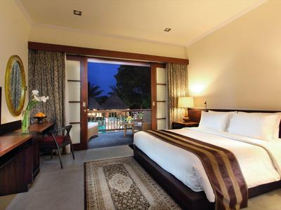 Moderne hotelkamer met groot bed en uitzicht op verlicht buitenzwembad.