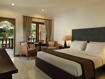 Moderne hotelkamer met tweepersoonsbed, balkon en zithoek met tafel en stoelen.