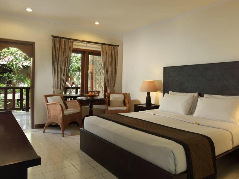 Moderne hotelkamer met tweepersoonsbed, balkon en zithoek met tafel en stoelen.