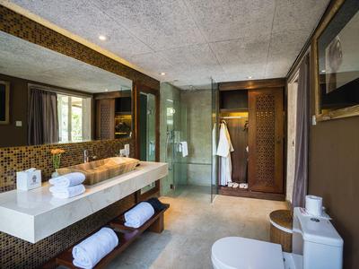 Baño moderno con gran espejo, lavabo, inodoro y ducha en una habitación de hotel.