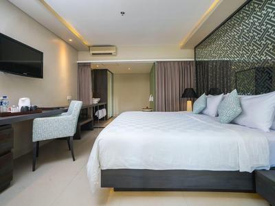 Habitación de hotel moderna con cama grande, escritorio, televisor y iluminación tenue.