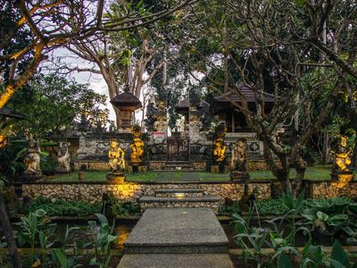 Garten mit Steinstatuen und einem Weg, der zu einem traditionellen Gebäude führt.