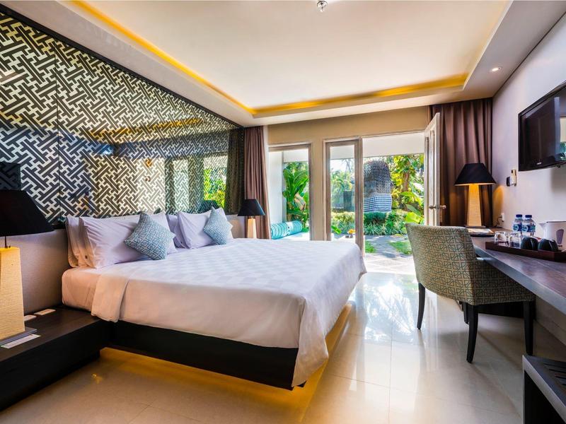 Habitación de hotel moderna con cama grande, iluminación elegante y vista a una terraza verde.