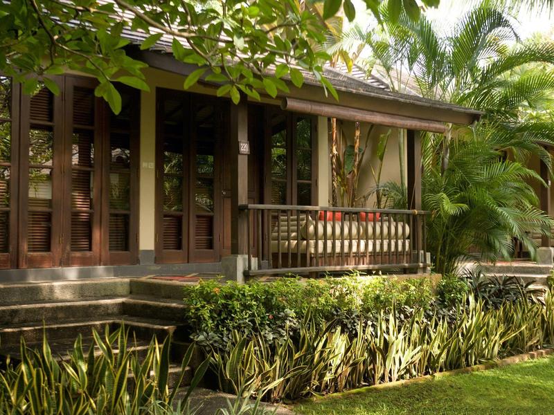 Un bungalow con terraza de madera y exuberante jardín tropical.