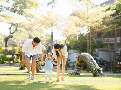 Ouders rennen met hun peuter op het gras in een hoteltuin.