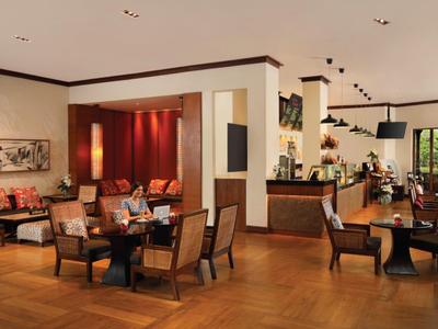 Gezellige hotel-lounge met fauteuils, houten vloer en warme verlichting.