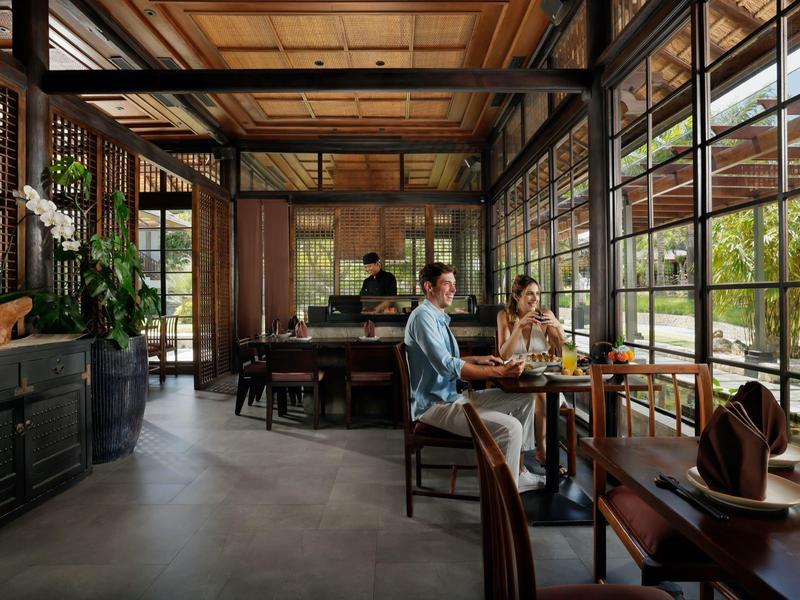 Twee mensen zitten in een lichte restaurant met houten accenten en grote ramen.