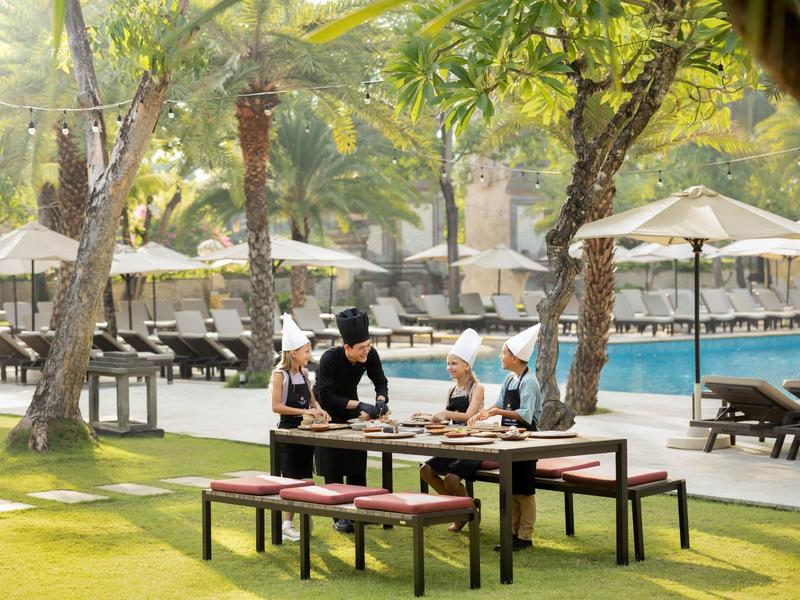 Gasten ontspannen aan een tafel in de schaduw naast het zwembad van het resort.