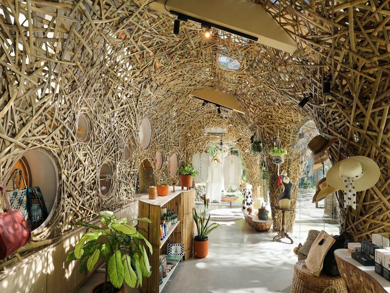 Interieur met verfijnd geweven hout- of bamboestructuren en planten in de ingang.