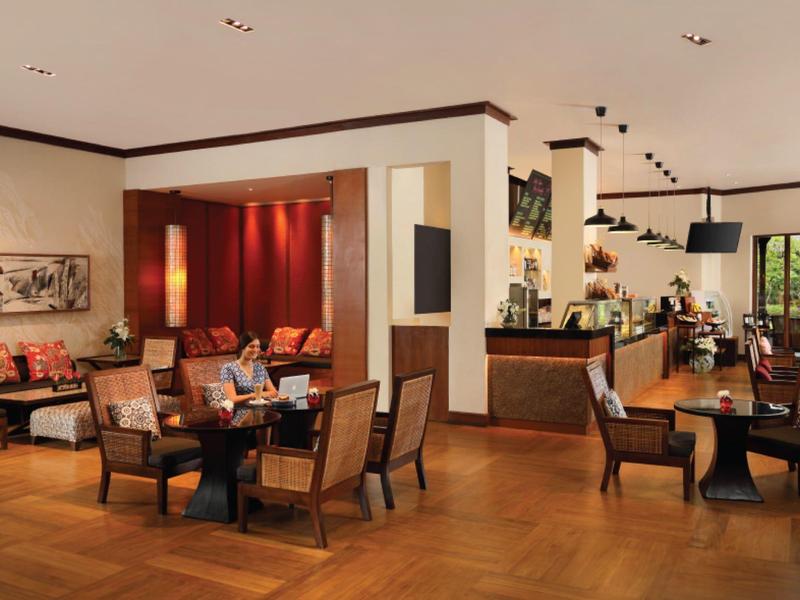 Gezellige hotel-lounge met fauteuils, houten vloer en warme verlichting.