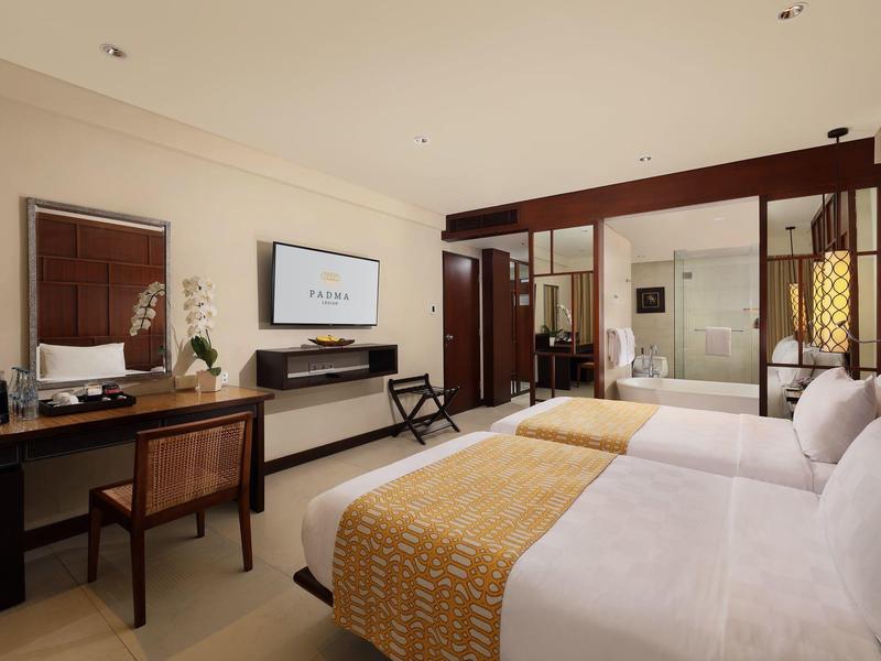 Moderne hotelkamer met twee bedden, bureau en glazen wand naar de badkamer.