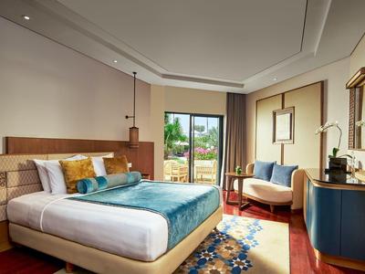 Chambre d'hôtel moderne avec lit double, coin salon et vue sur le jardin.