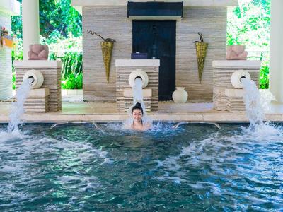 Personne se détend dans une piscine d'hôtel chauffée avec jeux d'eau et décorations.