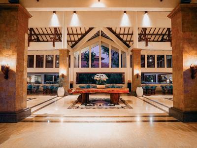 Hall d'hôtel élégant avec grande façade vitrée, espaces de sièges modernes et éclairage chaleureux