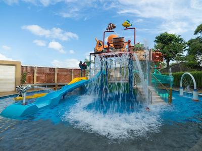 Aire de jeux aquatique colorée avec toboggans et jets d'eau dans un espace extérieur d'hôtel.