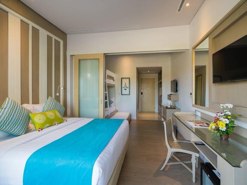 Chambre d'hôtel moderne avec lit, TV, bureau et fleurs fraîches.