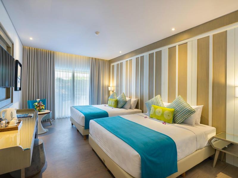 Chambre d'hôtel moderne avec deux lits, décoration élégante et grande fenêtre.