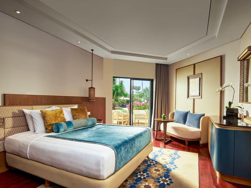 Chambre d'hôtel moderne avec lit double, coin salon et vue sur le jardin.