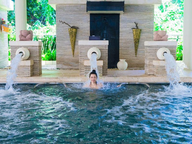 Personne se détend dans une piscine d'hôtel chauffée avec jeux d'eau et décorations.