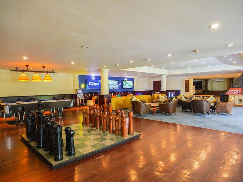 Espace salon spacieux d'hôtel avec des groupes de sièges et un grand échiquier au sol.